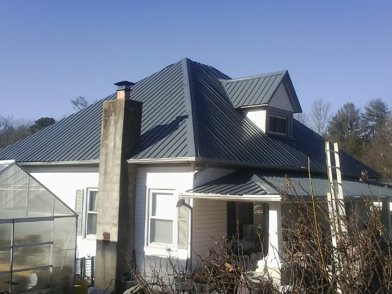 Dark blue standing seam metal roof on a white farmhouse with dormer — Slate & Tile Roof Repair by Roofing Brothers in Anderson Island