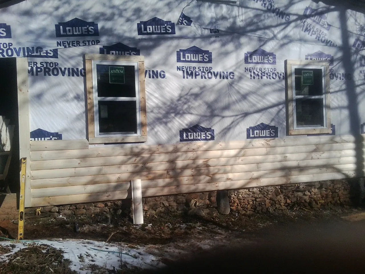 House wrap and new log siding going up on an exterior wall in Anderson Island
