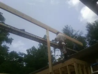 Carpenter setting a ridge beam over a new addition frame — Ice Dam Removal by Roofing Brothers in Anderson Island