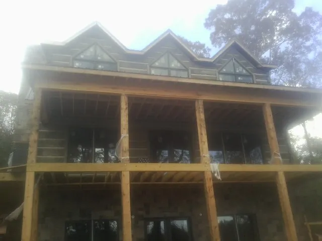 Dormers and porch framing on a large log home under construction — Roof Coating work by our crew in Anderson Island