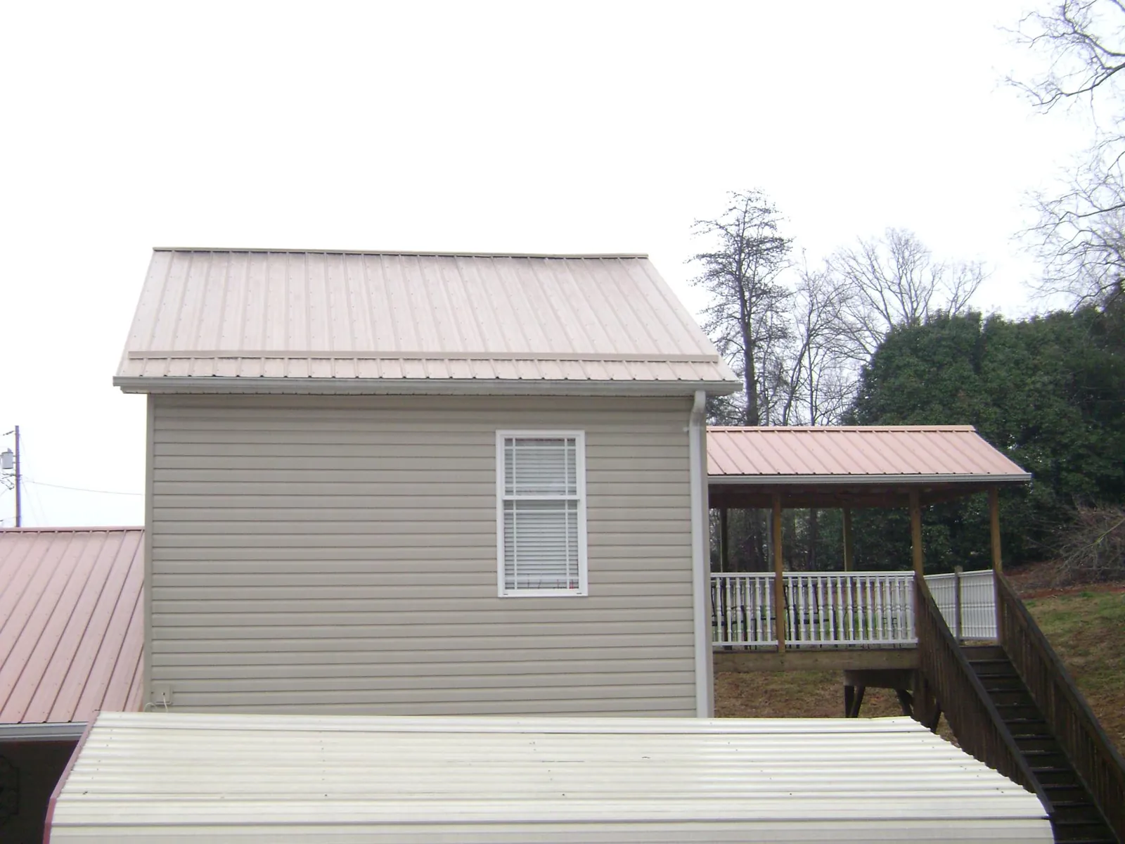 Tan metal roofs on a two story addition and attached porch, from a Roof Replacement job in Anderson Island