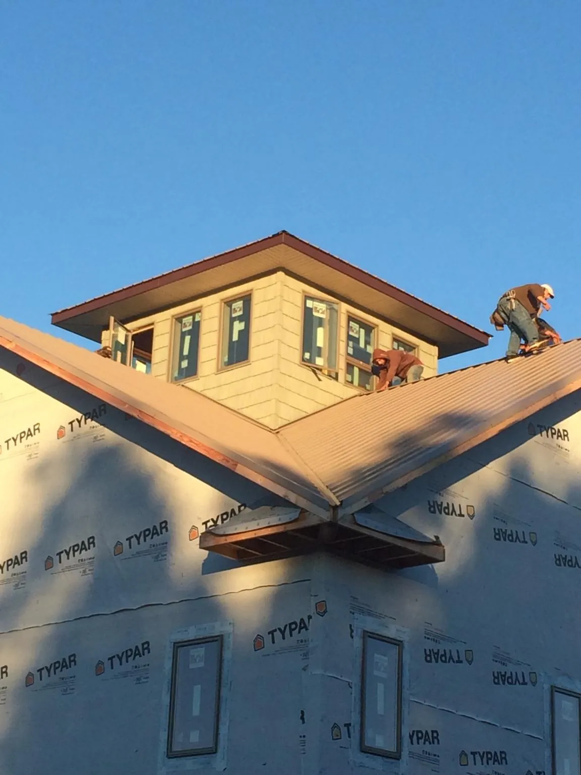 Roofers working around a rooftop cupola on a new metal roof at sunset — Roof Waterproofing in Anderson Island by Roofing Brothers